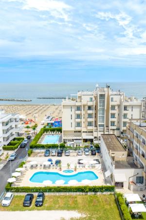 Vista panoramica su hotel, piscine e spiaggia con mare sullo sfondo.