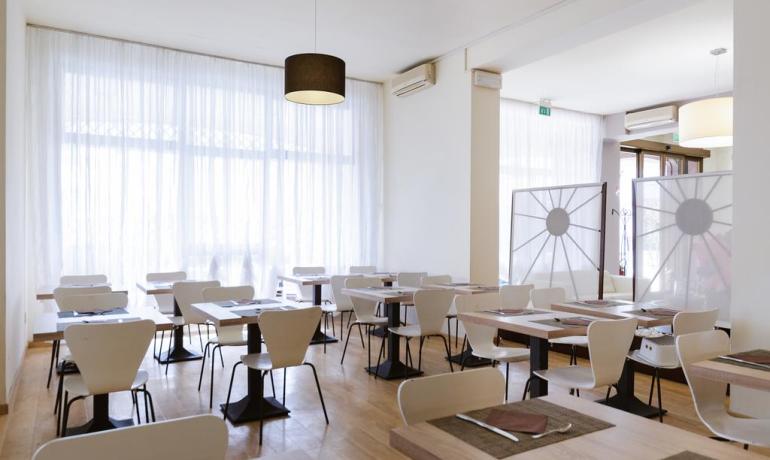 Modern restaurant with set tables and large windows.