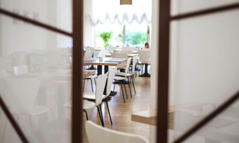 Empty restaurant with white chairs and wooden tables.